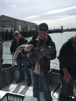 Man holding large fish at harbor dock smiling