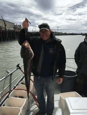 Man holding large fish on boat deck