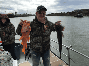 Man holding fish on boat during fishing trip