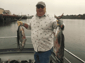 Man holding two large fish on boat dock