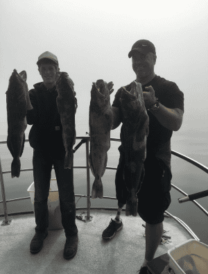 Two fishermen showing their catch on boat