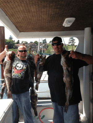 Two men proudly holding large fish on boat