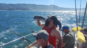 Fisherman holding catch on sunny ocean fishing trip