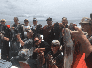 Group of fishermen showing off their catch at sea