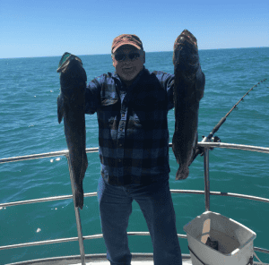 Man holding two large fish on boat