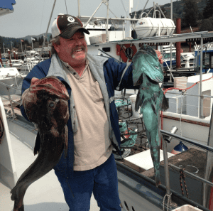 Man holding two large fish at marina