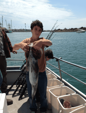 Boy holding large fish on boat deck