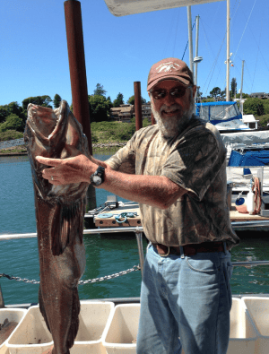 Man proudly holding large fish at marina