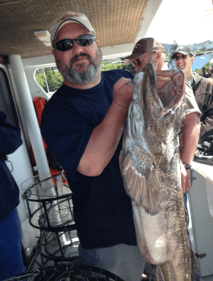 Man holding large fish on boat deck.
