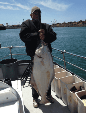 Fisherman holding large fish on boat deck