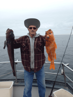 Man holding two fish on a boat at sea