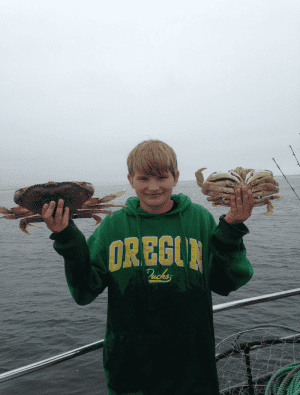 Boy holding crab on boat during fishing trip