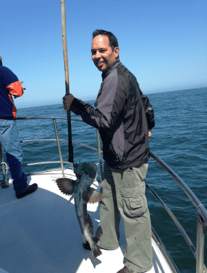 Man smiling with freshly caught fish at sea