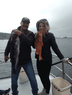 Two people showing their catch on a boat