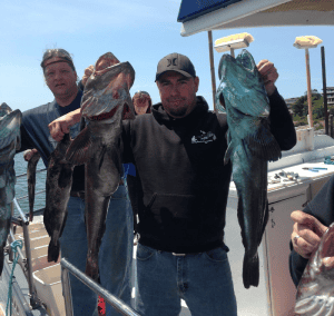 Fishermen holding large catches on boat deck