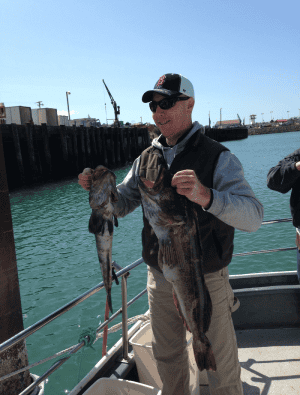 Man holding two large fish at the dock