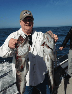 Man holding two large fish on boat
