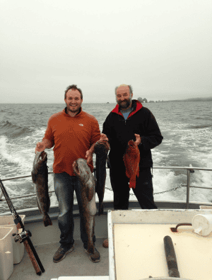 Two men showing off catch on fishing boat