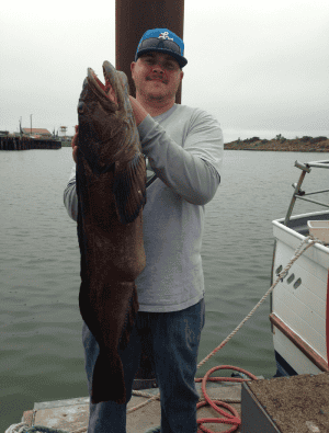 Man holding large fish at the harbor dock