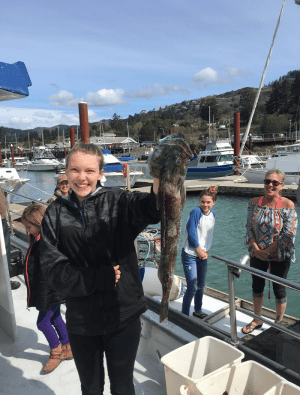 Young girl holding large fish at marina dock