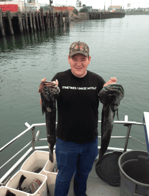 Man holding two fish at the dock.