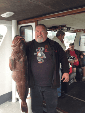Man holding large fish on boat with passengers